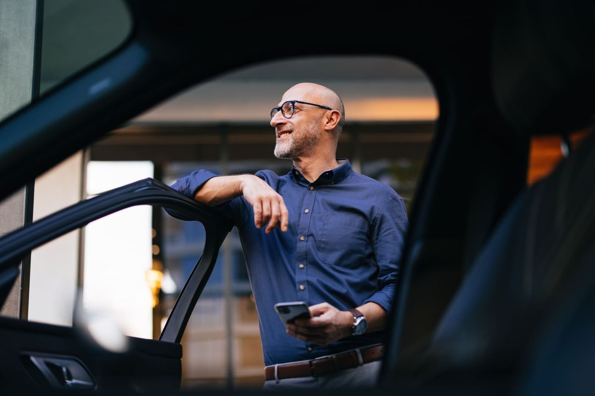 Een expat staat naast zijn private leaseauto